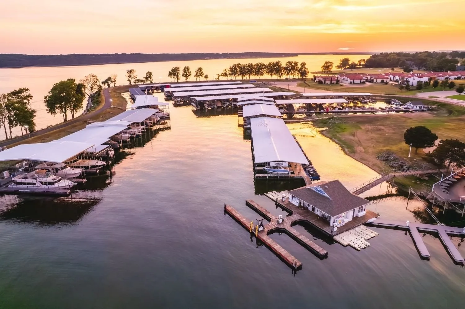 Aerial view of covered boat slips and docks along the Grand Lake shoreline at sunset near Shangri-La Resort